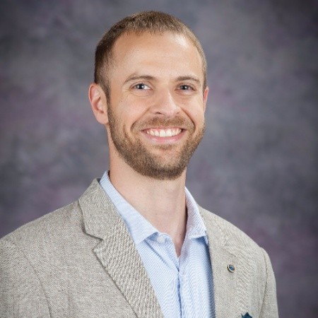 A person wearing a suit and tie smiling at the camera

Description automatically generated